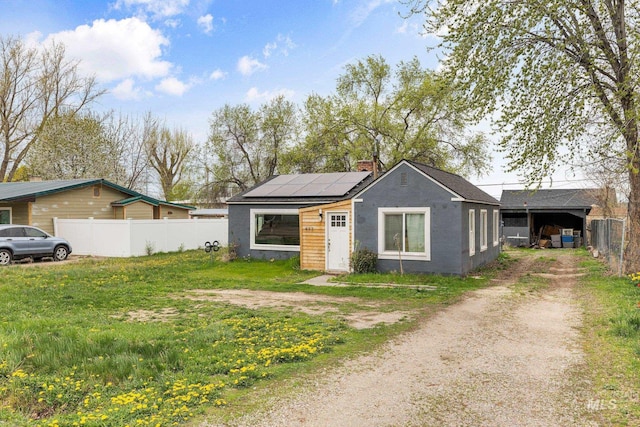 exterior space with solar panels, fence, and dirt driveway
