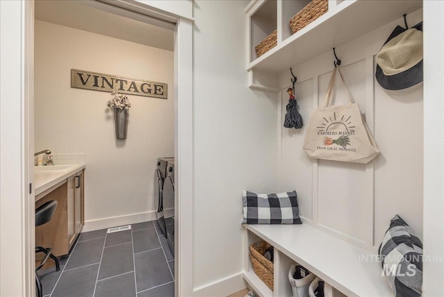 mudroom with sink and dark tile patterned floors