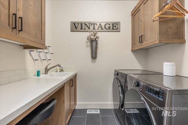 laundry area with sink, cabinets, dark tile patterned flooring, and washer and clothes dryer