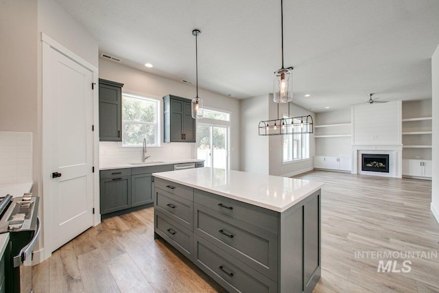 kitchen with a center island, sink, backsplash, pendant lighting, and a fireplace