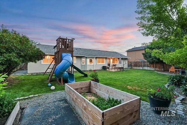 1722 W Mcglinchey St, Meridian, ID 83646 - back of property at dusk with a playground, a fenced backyard, a vegetable garden, and a patio