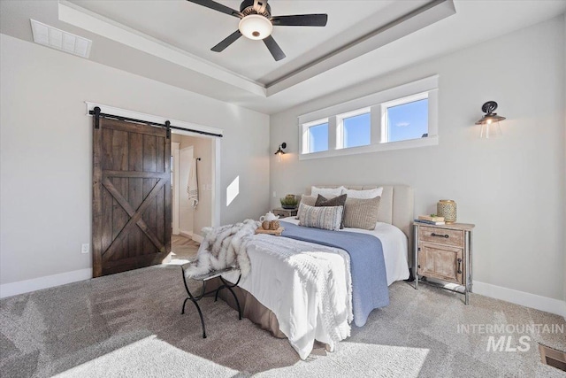 carpeted bedroom featuring a raised ceiling, visible vents, a barn door, ensuite bath, and baseboards