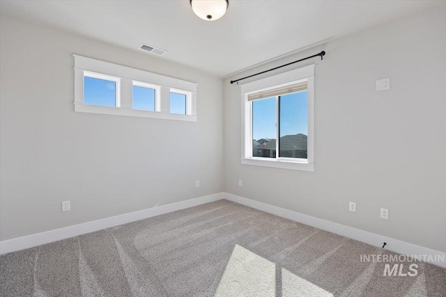 spare room featuring carpet, visible vents, and baseboards