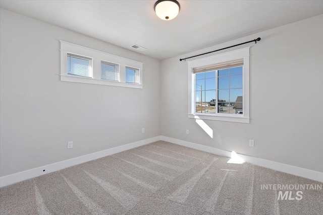 carpeted spare room with visible vents and baseboards