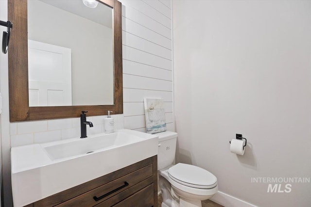 bathroom featuring vanity, toilet, and decorative backsplash