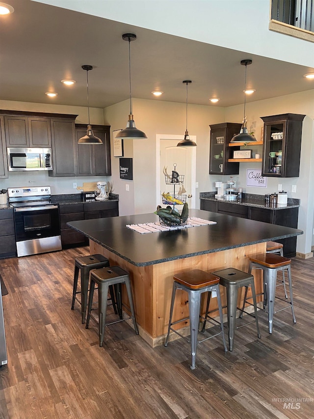 kitchen featuring a center island, a kitchen breakfast bar, dark hardwood / wood-style floors, and appliances with stainless steel finishes