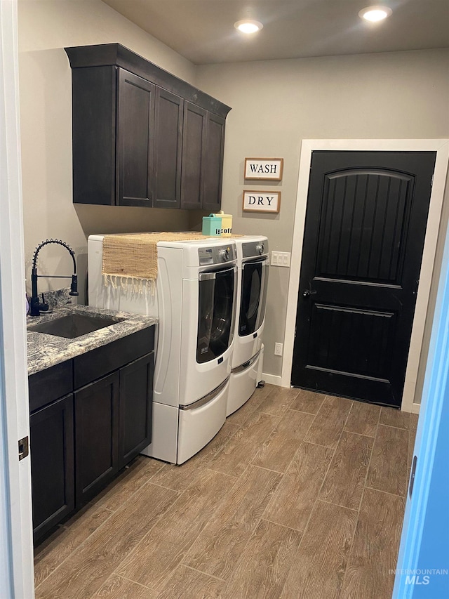 clothes washing area featuring light hardwood / wood-style flooring, cabinets, sink, and washing machine and dryer