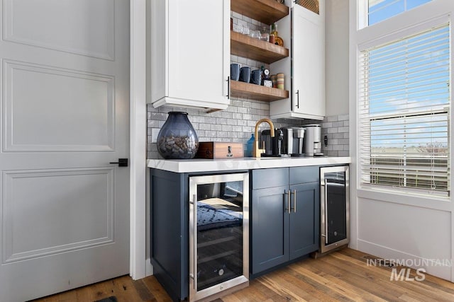 bar featuring a healthy amount of sunlight, light hardwood / wood-style floors, and beverage cooler