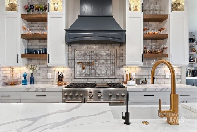 kitchen with decorative backsplash, light stone counters, and custom exhaust hood