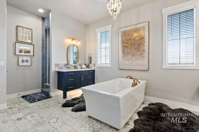 bathroom featuring vanity, a bath, and an inviting chandelier