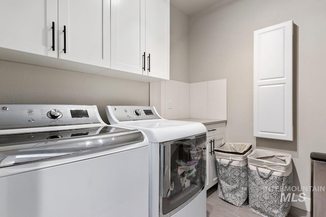 washroom with washer and dryer, light hardwood / wood-style flooring, and cabinets