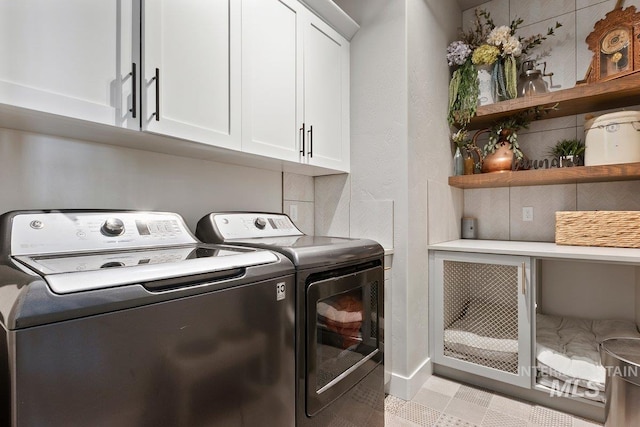 washroom featuring washing machine and dryer and cabinets