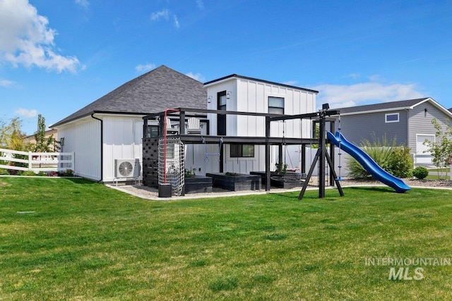 rear view of property with ac unit, a playground, and a lawn