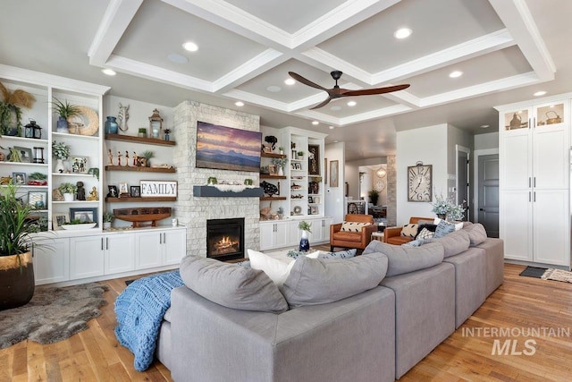 living room with coffered ceiling, light hardwood / wood-style flooring, ceiling fan, a fireplace, and beam ceiling