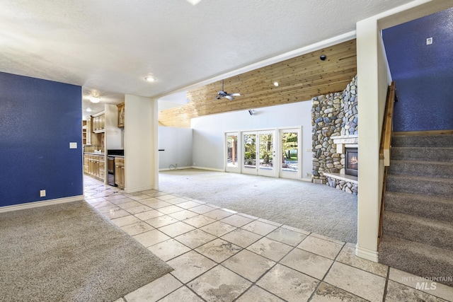 70 Pelican Dr, Rupert, ID 83350 - unfurnished living room featuring light colored carpet, a stone fireplace, light tile patterned floors, stairs, and baseboards