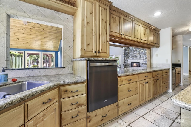 70 Pelican Dr, Rupert, ID 83350 - kitchen with stainless steel dishwasher, a textured ceiling, light stone countertops, a fireplace, and a sink