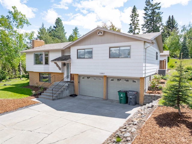 1205 Ponderosa Dr, Moscow, ID 83843 - raised ranch featuring brick siding, a chimney, an attached garage, driveway, and roof with shingles