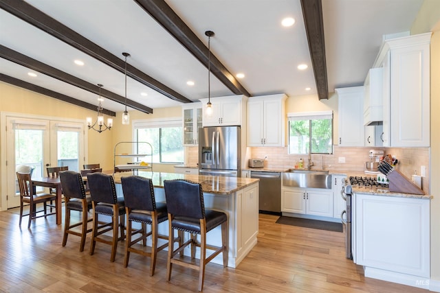 1205 Ponderosa Dr, Moscow, ID 83843 - kitchen with appliances with stainless steel finishes, a sink, white cabinetry, tasteful backsplash, and a center island with sink