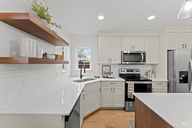 kitchen featuring decorative backsplash, appliances with stainless steel finishes, light wood-type flooring, sink, and white cabinetry