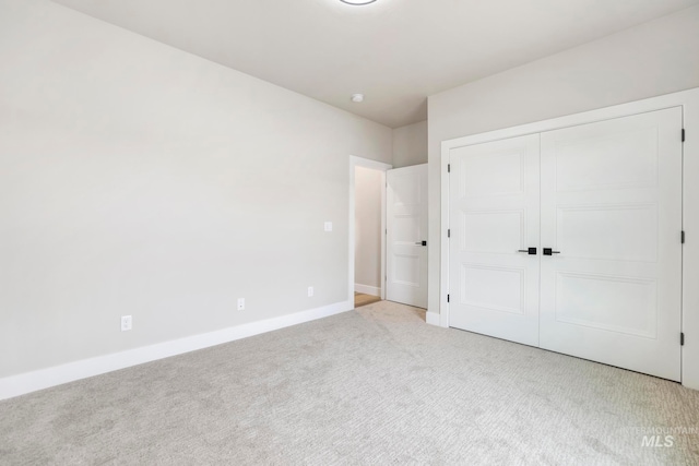 unfurnished bedroom featuring light carpet and a closet