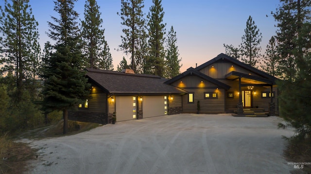 view of front of property featuring a chimney, an attached garage, stone siding, and concrete driveway