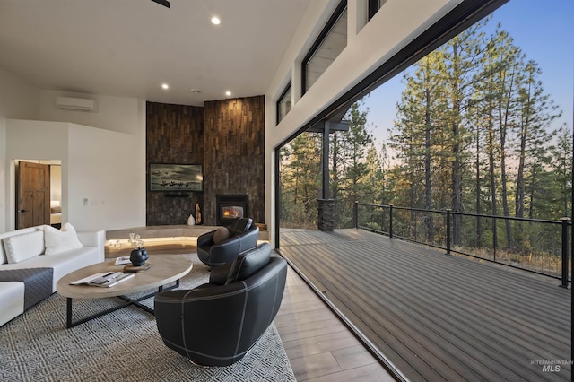 living room with light wood finished floors, a wall mounted air conditioner, a large fireplace, and recessed lighting
