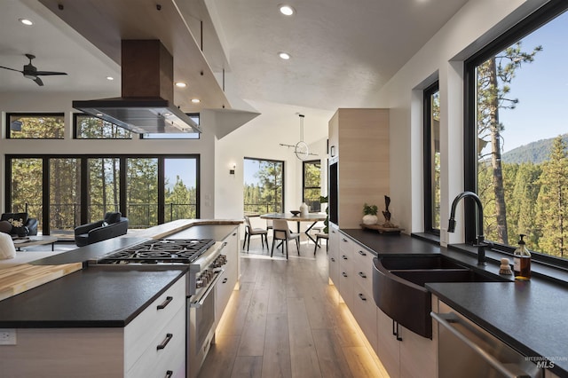 kitchen with dark countertops, white cabinets, appliances with stainless steel finishes, and a sink