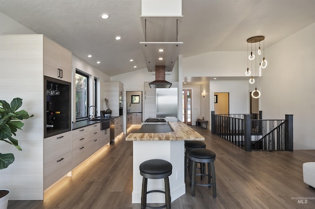 kitchen with modern cabinets, vaulted ceiling, a center island, butcher block countertops, and island range hood