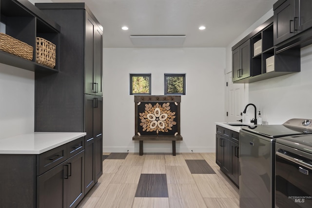 kitchen featuring open shelves, a sink, light countertops, recessed lighting, and washing machine and clothes dryer