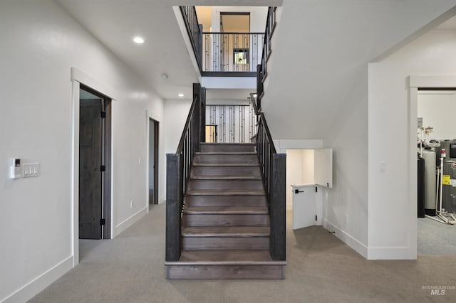 stairs with electric water heater, recessed lighting, baseboards, and carpet floors