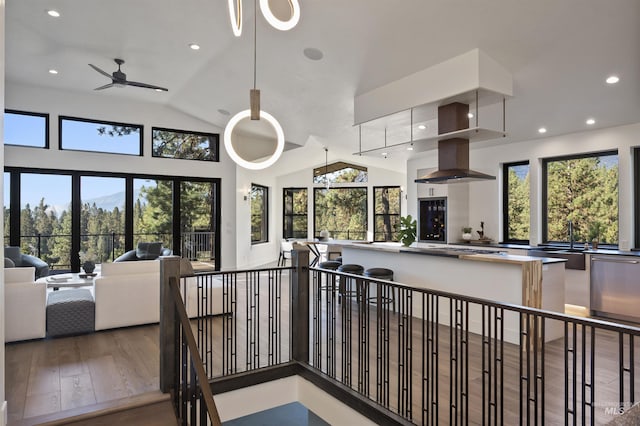 interior space with open floor plan, a healthy amount of sunlight, wood finished floors, and island exhaust hood