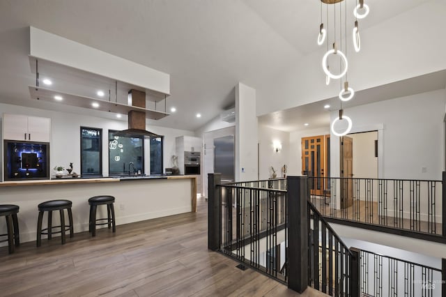 interior space featuring white cabinets, a sink, fridge, wood finished floors, and vaulted ceiling
