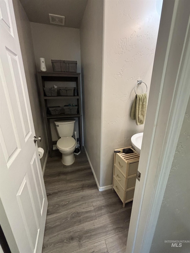 4618 Braeburn, Caldwell, ID 83607 - half bath with vanity, baseboards, toilet, visible vents, and wood finished floors