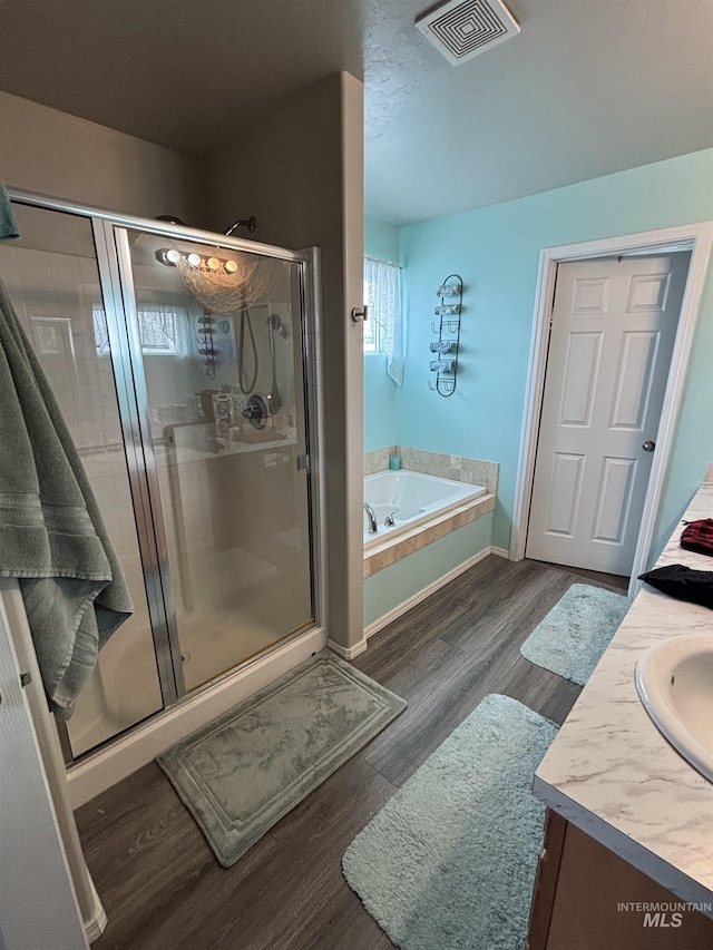 4618 Braeburn, Caldwell, ID 83607 - full bath featuring vanity, a shower stall, visible vents, a garden tub, and wood finished floors