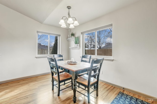 dining space with an inviting chandelier, light wood-style floors, and baseboards