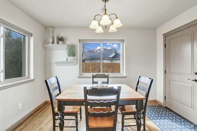 dining space with a wealth of natural light, a notable chandelier, baseboards, and light wood-style floors