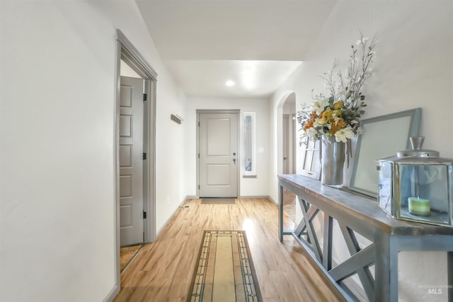 hallway featuring baseboards, arched walkways, and wood finished floors