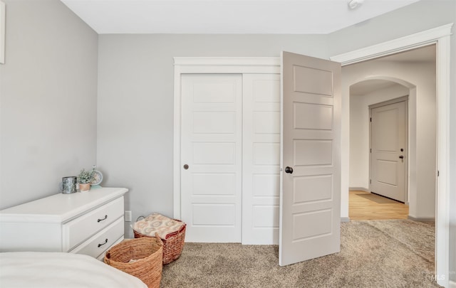 carpeted bedroom with arched walkways and a closet