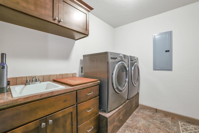 clothes washing area with washer and clothes dryer, stone finish floor, electric panel, cabinet space, and a sink