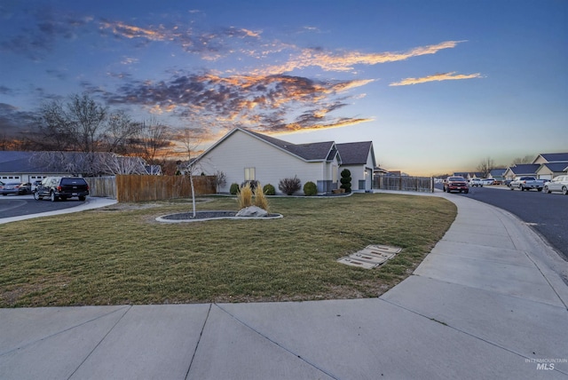 property exterior at dusk featuring fence and a lawn