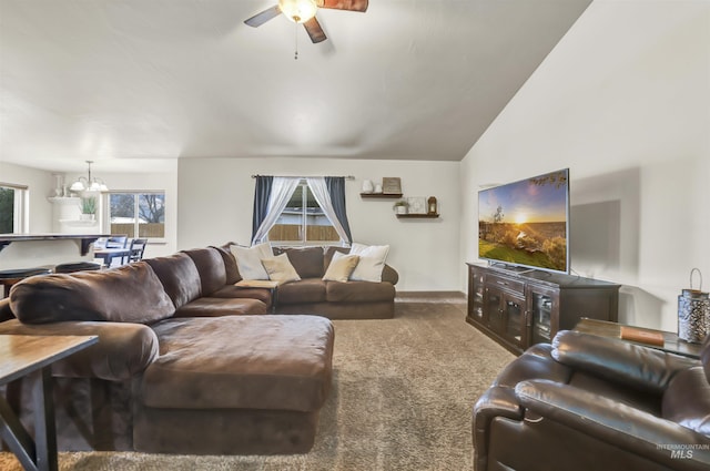 living area featuring ceiling fan with notable chandelier, carpet, and vaulted ceiling