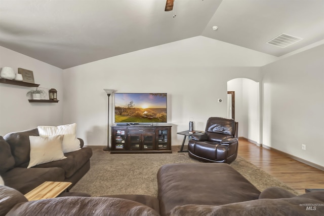 living area featuring visible vents, a ceiling fan, wood finished floors, arched walkways, and vaulted ceiling