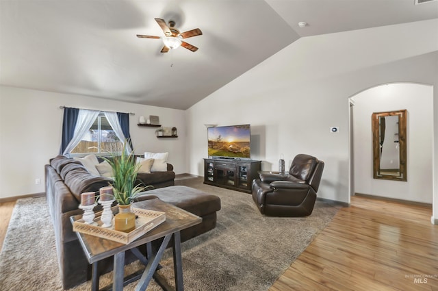 living area with visible vents, vaulted ceiling, light wood-style flooring, arched walkways, and a ceiling fan