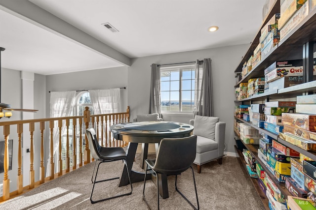 carpeted dining area with beam ceiling