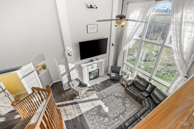 living room with ceiling fan, a high ceiling, and dark hardwood / wood-style floors