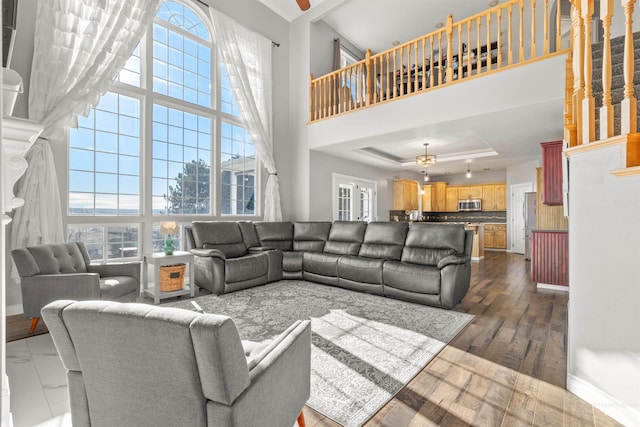 living room featuring ceiling fan, dark hardwood / wood-style flooring, a raised ceiling, and a towering ceiling