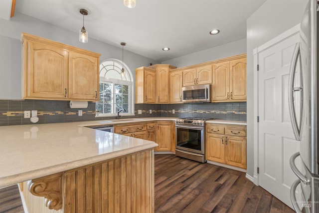 kitchen featuring appliances with stainless steel finishes, decorative light fixtures, dark hardwood / wood-style flooring, sink, and kitchen peninsula