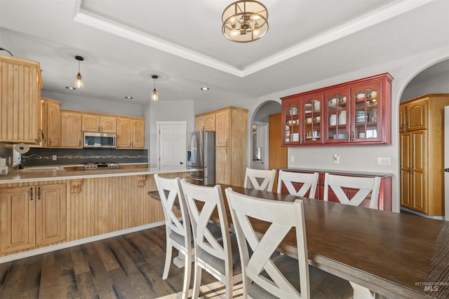 kitchen featuring decorative light fixtures, kitchen peninsula, a raised ceiling, and stainless steel appliances