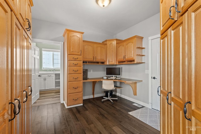 office area with dark wood-type flooring and built in desk