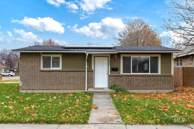 view of front of house featuring solar panels and a front lawn